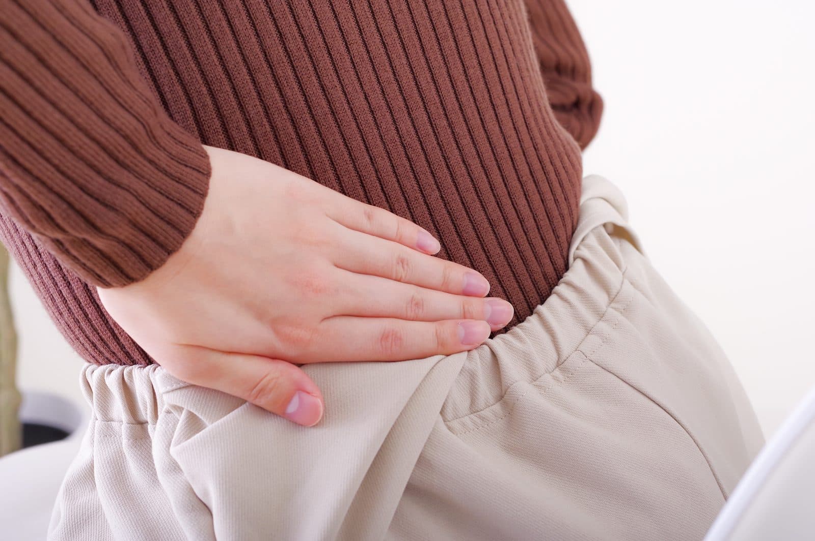 立ち仕事の途中で腰に手をあてる様子