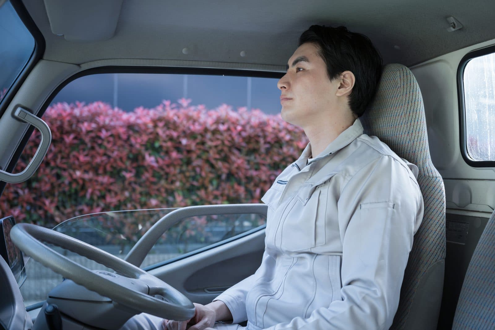 運転席の背もたれに身を預けて休むドライバー