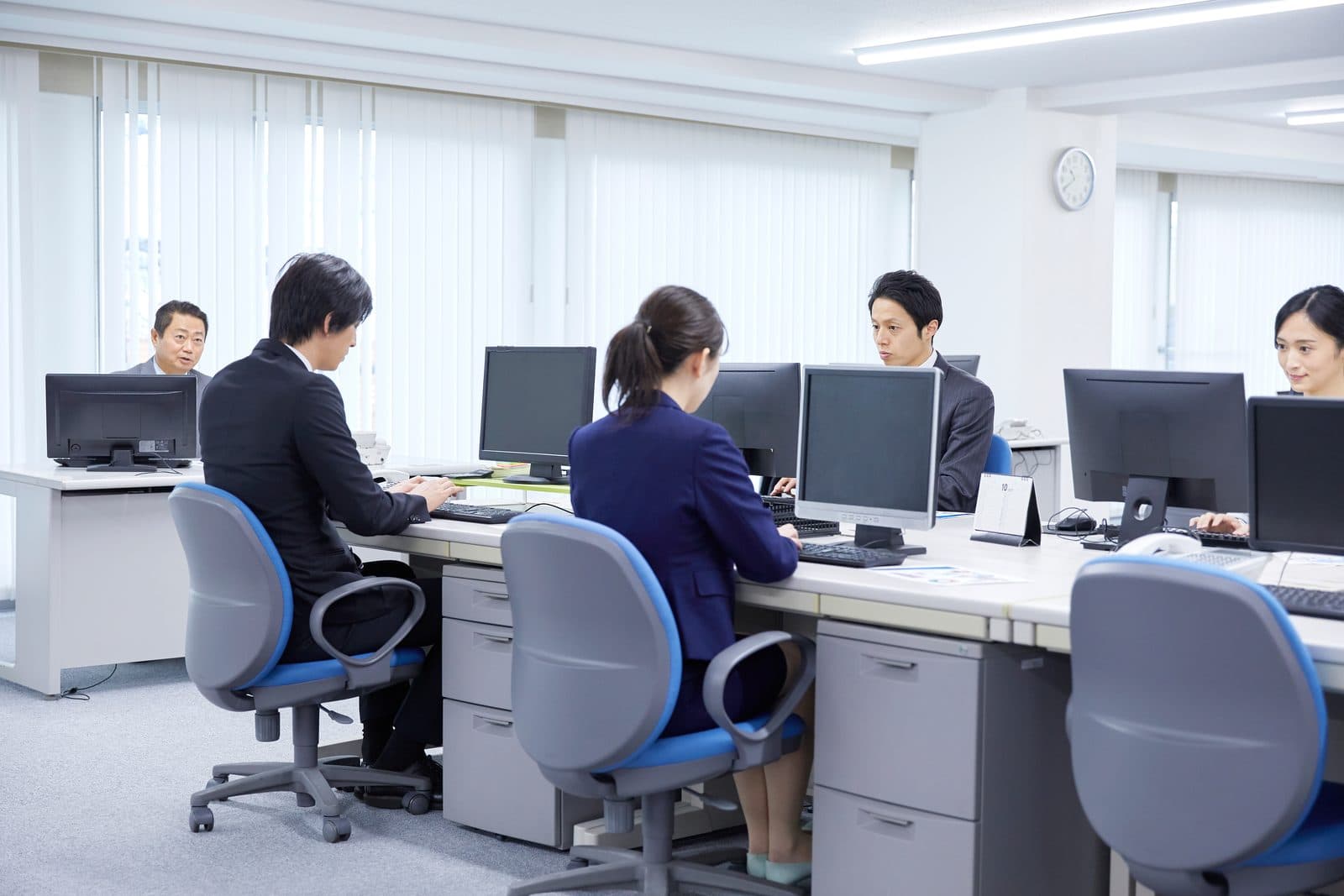 机が並んだ事務所で、それぞれの画面に向かって働く人たち