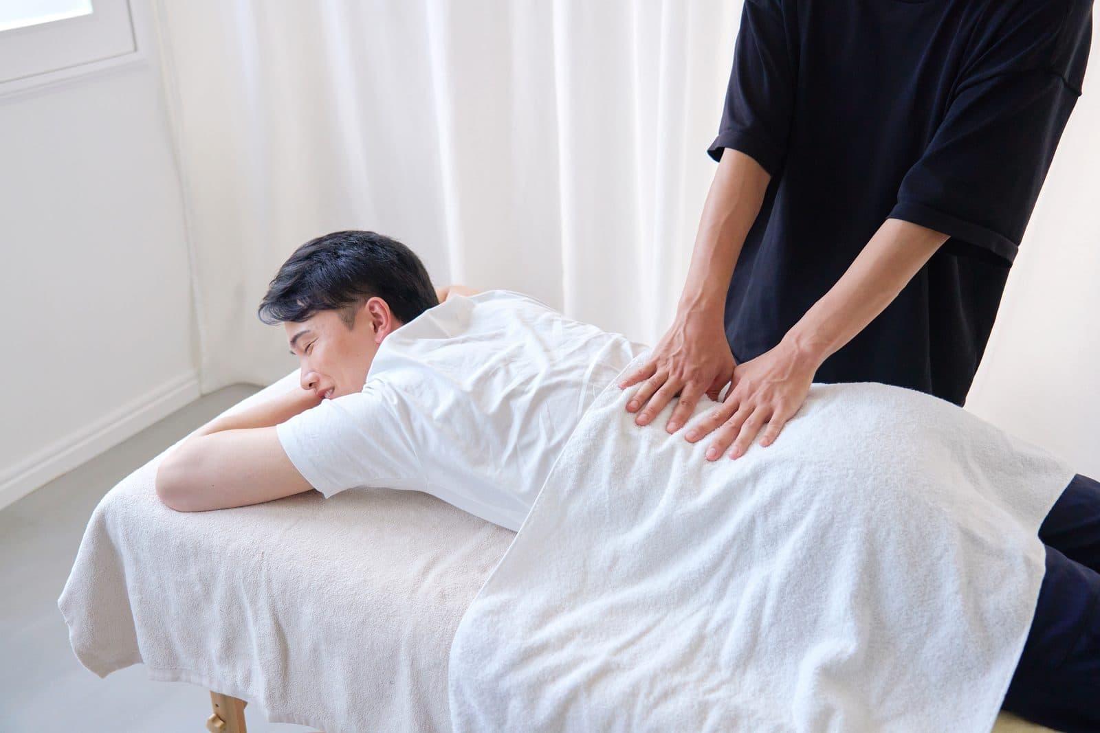施術台でうつ伏せになり、腰まわりのケアを受けている人