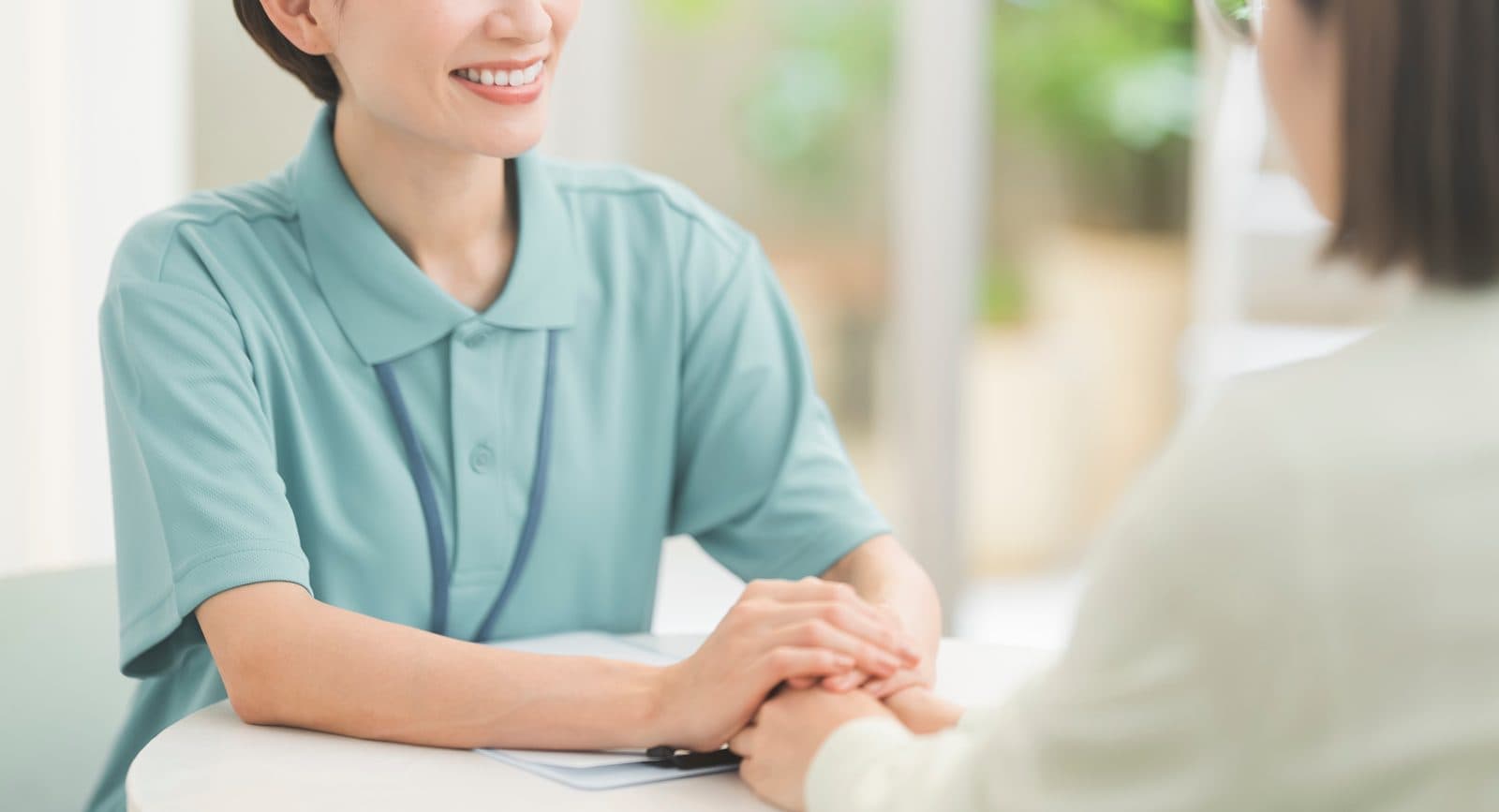 相談者の手をとって、向かい合って話を聞く相談員